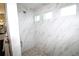 Modern shower with marble-look tile, mosaic floor, and bright natural light from three windows at 9529 Calumet Blvd, Port Charlotte, FL 33981