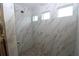 Luxurious walk-in shower featuring elegant marble-look tile, modern fixtures, and refreshing natural light at 9529 Calumet Blvd, Port Charlotte, FL 33981