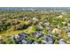 An aerial view showing mature trees, green lawns, and an array of homes with solar panels and screened pools at 1068 Harbour Cape Pl, Punta Gorda, FL 33983