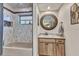 Well-lit bathroom featuring a tub-shower combo, a granite vanity, and a round mirror at 1068 Harbour Cape Pl, Punta Gorda, FL 33983