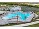 Aerial view of a resort-style pool, tennis courts, and clubhouse surrounded by lush landscaping and walking paths at 14381 Heritage Landing Blvd, Punta Gorda, FL 33955