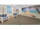 Cozy sitting area with beach mural, coastal decor, and comfortable wicker chairs at 25188 Marion Ave # E409, Punta Gorda, FL 33950