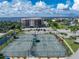 Aerial view of tennis courts with a condo building and waterfront in the background at 25188 Marion Ave # E409, Punta Gorda, FL 33950