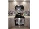 Modern kitchen with stainless steel range and microwave, gray cabinetry, and updated backsplash, ideal for cooking and entertaining at 25472 Tevesine Ct, Punta Gorda, FL 33983