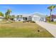 Inviting home featuring verdant lawn, mature palms and vibrant front garden landscape at 25730 Deep Creek Blvd, Punta Gorda, FL 33983
