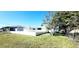 Expansive backyard view featuring lush green grass, trees, and a glimpse of the home's exterior at 3372 Elkcam Blvd, Port Charlotte, FL 33952