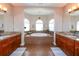 Bright bathroom featuring double vanities, granite countertops and a large tub beneath arched windows at 3606 Whippoorwill Blvd, Punta Gorda, FL 33950