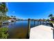 Scenic waterfront view featuring a concrete dock, boats, calm canal waters, and clear blue skies at 3606 Whippoorwill Blvd, Punta Gorda, FL 33950