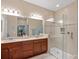 Elegant bathroom featuring double sinks, granite countertop, and a spacious glass-enclosed shower with tiled walls at 10357 Crooked Creek Dr, Venice, FL 34293