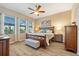 Comfortable bedroom with a wooden bed frame, ceiling fan, and three windows, providing natural light and style at 10357 Crooked Creek Dr, Venice, FL 34293