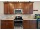 Kitchen featuring stainless steel appliances, dark wood cabinets, granite countertops, and tile backsplash at 10357 Crooked Creek Dr, Venice, FL 34293