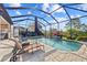 Screened-in pool area with comfortable lounge chairs and a serene waterfall feature at 10357 Crooked Creek Dr, Venice, FL 34293