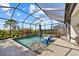 Screened-in pool area with blue lounge chairs and lush landscaping at 10357 Crooked Creek Dr, Venice, FL 34293