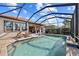 Outdoor pool with clear water, lounge chairs, lush landscaping and screened-in patio at 10357 Crooked Creek Dr, Venice, FL 34293