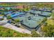 Aerial of tennis courts; showcasing green courts, palms, clubhouse, parking, pool and more at 10357 Crooked Creek Dr, Venice, FL 34293