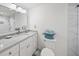 Well-lit bathroom features a marble-top vanity with dual sinks, a toilet with a wicker basket, and sleek finishes at 1212 Benjamin Franklin Dr # 102, Sarasota, FL 34236
