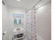 Cozy bathroom featuring a shower with colorful fish curtain, white walls, and a small vanity with beach themed decor at 1212 Benjamin Franklin Dr # 102, Sarasota, FL 34236