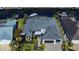 Aerial view of the modern home featuring a dark roof, a two car garage and lush landscaping at 1230 Royal Tern Dr, Punta Gorda, FL 33950