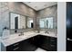 Bathroom featuring dual vanity with marble countertop, black cabinets, and stone accent wall at 1230 Royal Tern Dr, Punta Gorda, FL 33950