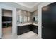 Bathroom featuring dual vanity with marble countertop, black cabinets, stone wall, and laundry access at 1230 Royal Tern Dr, Punta Gorda, FL 33950