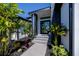 Striking home entrance featuring sleek black door, stone accents, and lush tropical landscaping at 1230 Royal Tern Dr, Punta Gorda, FL 33950