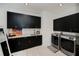 Well-equipped laundry room with black cabinets, marble countertops, stainless steel sink, and modern washer/dryer at 1230 Royal Tern Dr, Punta Gorda, FL 33950