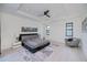 Spacious bedroom with white wood-look floors, tray ceiling, ceiling fan, and cozy gray accent chair at 1230 Royal Tern Dr, Punta Gorda, FL 33950