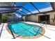 Inviting screened-in pool area with a clear blue pool, sunny patio, and lush landscaping at 16249 Ashland Ave, Port Charlotte, FL 33954