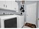 Well-lit laundry room with white cabinets, modern appliances, and a convenient hanging pot rack at 1701 Lastingham Ln, Port Charlotte, FL 33980