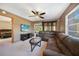 Open-concept living room leading to a bedroom featuring tan carpet, ceiling fan, and leather furniture at 179 Boundary Blvd # 4, Rotonda West, FL 33947