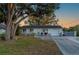 Charming single-story home with a well-maintained lawn, mature tree, and a long driveway leading to a one-car garage at 18417 Ohara Dr, Port Charlotte, FL 33948