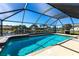 Screened-in pool area with clear blue water and a view of the canal and dock, great for relaxing outdoors at 18462 Alphonse Cir, Port Charlotte, FL 33948