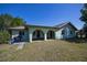 Back exterior featuring an arched, covered patio and spacious, well-maintained yard at 23051 Elmira Blvd, Punta Gorda, FL 33980