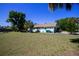 Rear exterior of home showcasing side yard, mature trees and landscaping, and neutral color palette at 23051 Elmira Blvd, Punta Gorda, FL 33980
