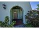 Covered front entryway featuring an arched doorway and tiled walkway framed by lush landscaping at 23051 Elmira Blvd, Punta Gorda, FL 33980