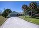 Charming single-story home featuring a long driveway, two-car garage, and mature palm trees at 23051 Elmira Blvd, Punta Gorda, FL 33980