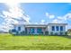 The back exterior of the home displays a covered patio, lush lawn, and meticulous landscaping at 24166 Colima Ct, Punta Gorda, FL 33955