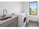 The laundry room includes a sink, quartz counters, stainless faucet, and a front-load washer and dryer at 24166 Colima Ct, Punta Gorda, FL 33955
