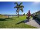 Picturesque backyard featuring green grass, lake views, patio seating, and a secure fence for privacy at 27002 Clear Creek Way, Punta Gorda, FL 33950