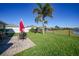 Well-manicured backyard with a brick patio, seating, a palm tree, and a view of the lake at 27002 Clear Creek Way, Punta Gorda, FL 33950