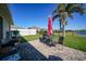 Paver patio with seating area and umbrella overlooks the manicured lawn and lake at 27002 Clear Creek Way, Punta Gorda, FL 33950