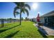 Spacious backyard with a well-manicured lawn, patio seating, lake view, and fenced perimeter at 27002 Clear Creek Way, Punta Gorda, FL 33950