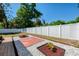 A backyard featuring a white vinyl fence, decorative stones, and a brick patio, complemented by lush greenery at 3172 Sikeston Ave, North Port, FL 34286