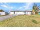 Single-story home with a white exterior, concrete driveway, and well-maintained lawn on a sunny day at 3243 Elkcam Blvd, Port Charlotte, FL 33952