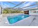An outdoor pool is surrounded by a screened enclosure with a view of trees beyond at 3243 Elkcam Blvd, Port Charlotte, FL 33952