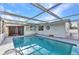 Sparkling in-ground pool surrounded by a screened enclosure with a sunny blue sky above at 3243 Elkcam Blvd, Port Charlotte, FL 33952