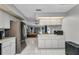 A bright kitchen featuring white cabinets, stainless steel refrigerator, white tile flooring, and open access to the living room at 3880 Pinstar Ter, North Port, FL 34287