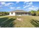 Backyard view of the lanai, house, and a firepit in the lawn, with clear blue skies overhead at 422 Ravenswood Blvd, Port Charlotte, FL 33954