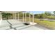 View of the screened-in lanai with a door that leads to the green backyard and a black welcome mat on the porch's concrete floor at 422 Ravenswood Blvd, Port Charlotte, FL 33954