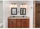 Bathroom featuring double sinks with granite counters, wood cabinets, and tiled walls at 5125 Ariton Rd, North Port, FL 34288